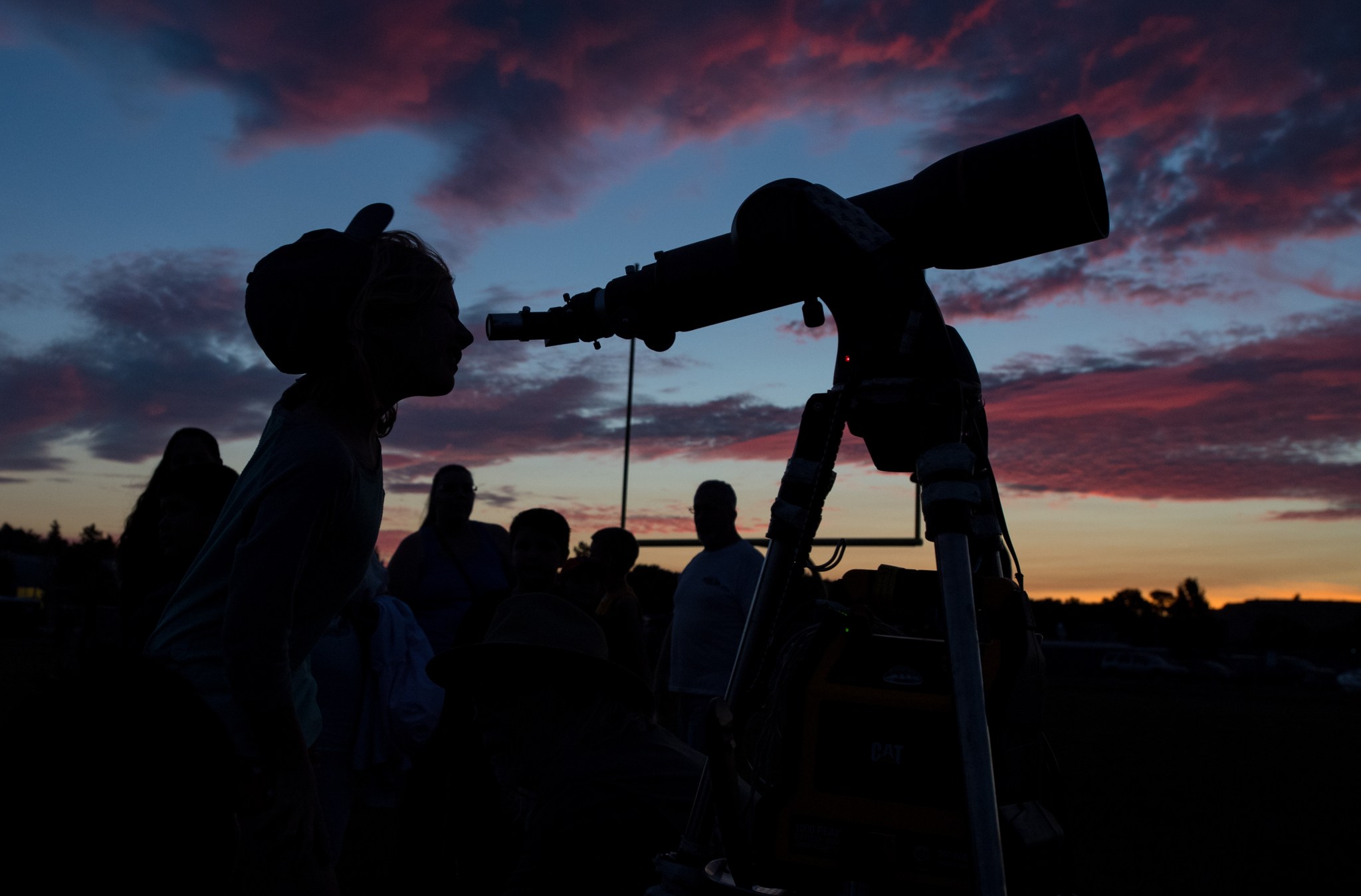 黄昏时透过望远镜观看的人