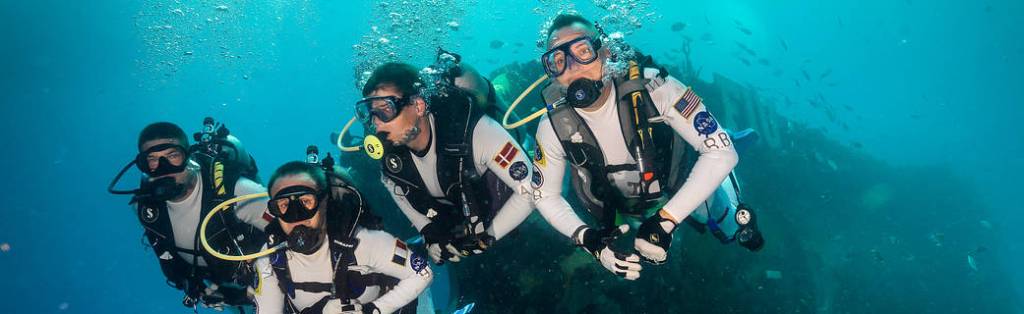 Photo of astronaut crew undersea with Aquarius Habitat in background