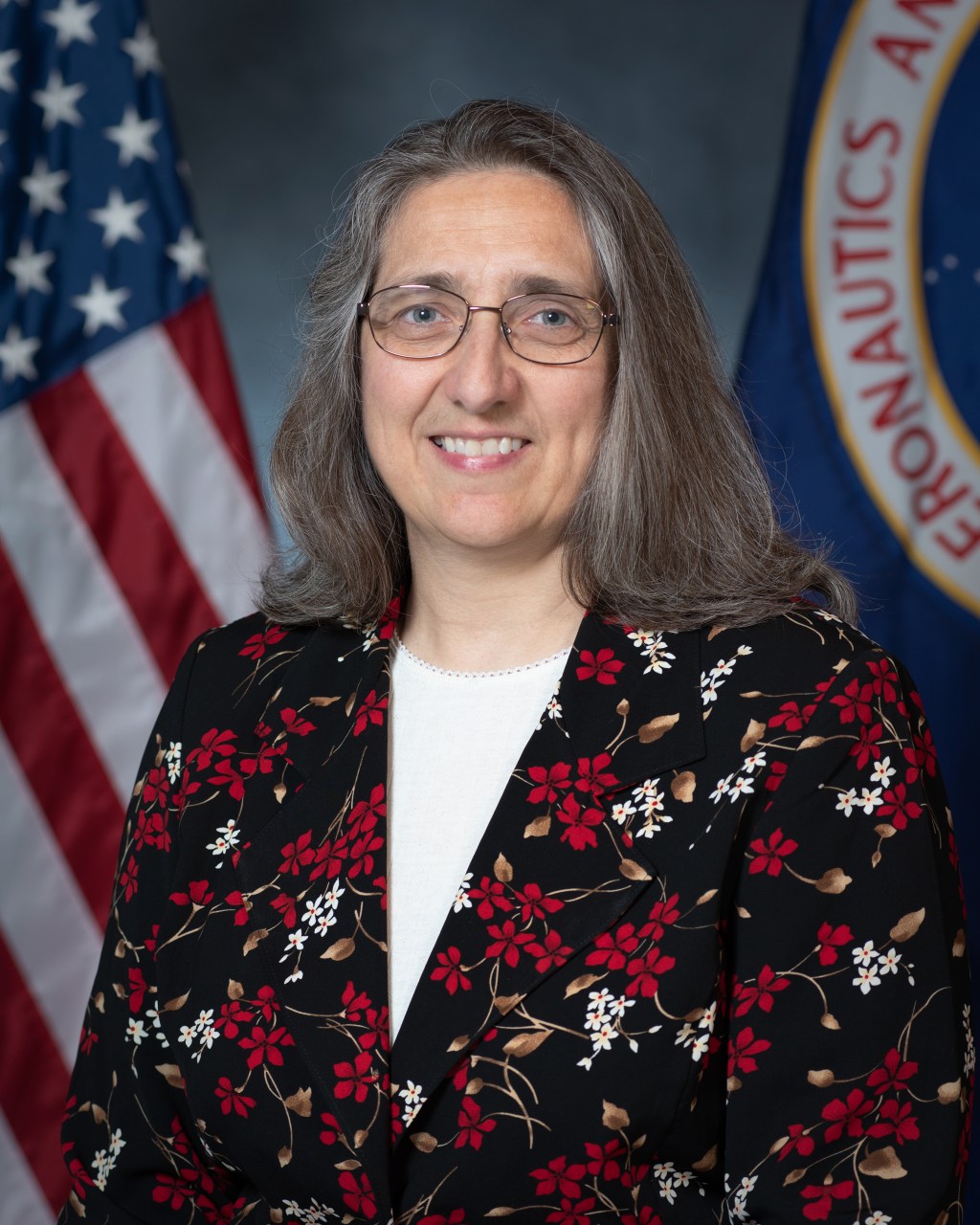 Portrait of Maria Babula with U.S. and NASA flags in background.
