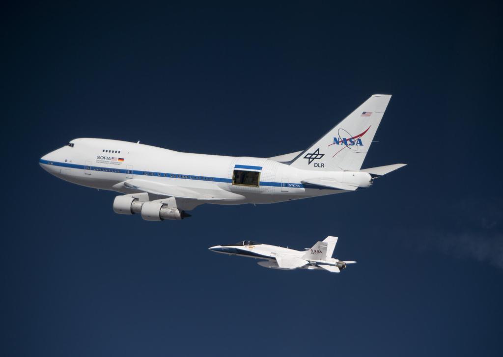 NASA's SOFIA aircraft in flight with the F/A-18 airplane underneath it.