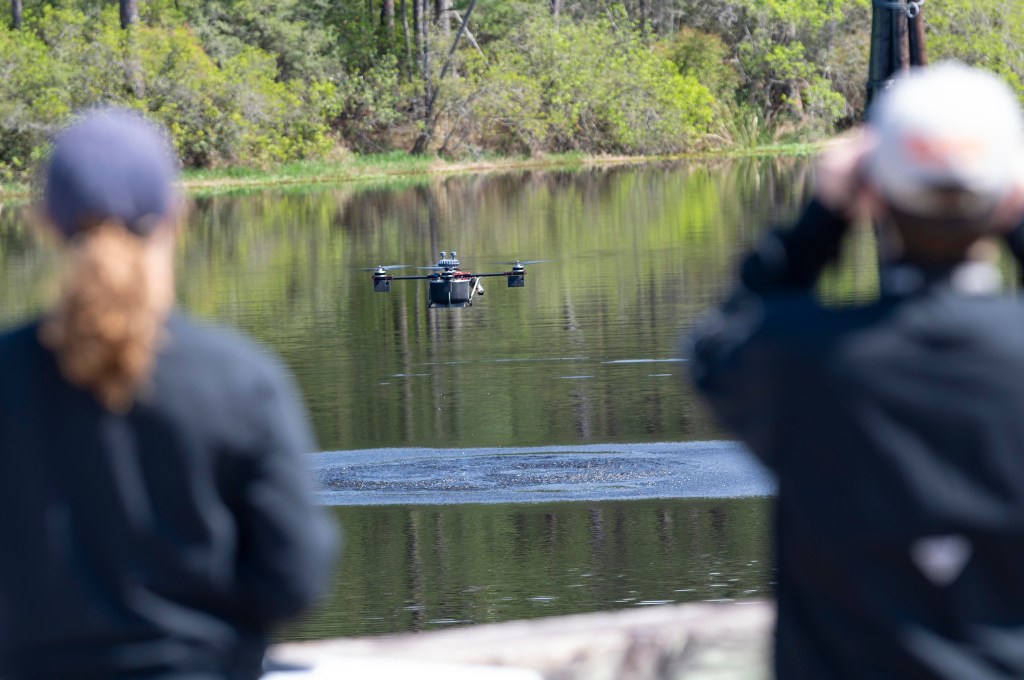 Drone people pilot a drone flying low over a body of water