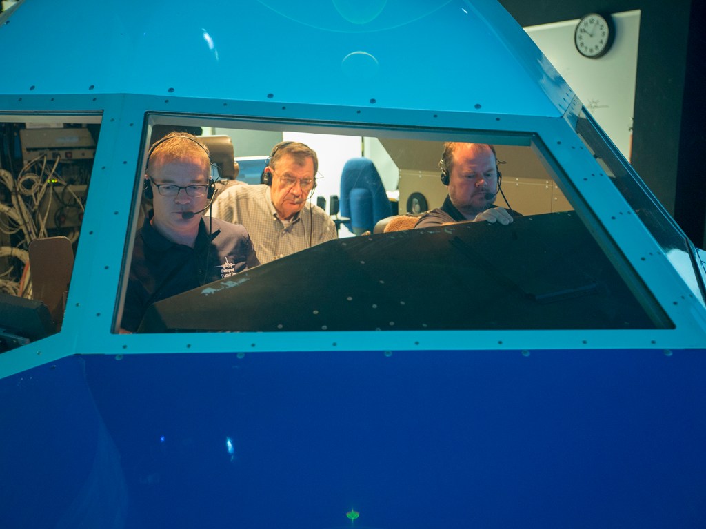Three men inside a cockpit.