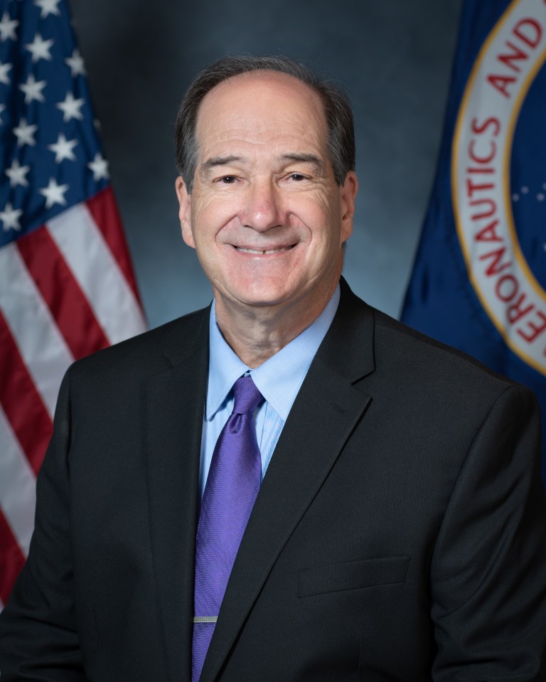 Portrait of Scott Graham with U.S. and NASA flags in the background.