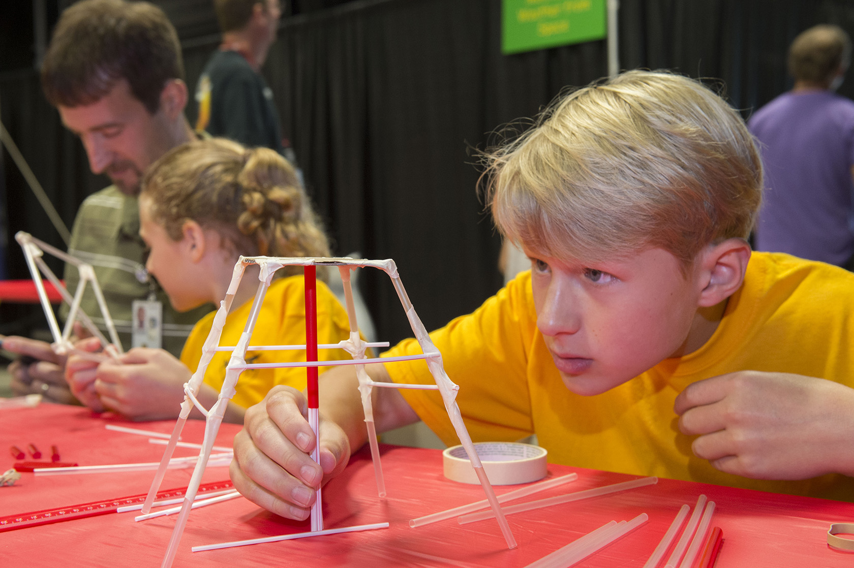 Nate Maehlmann, right, and his sister Clara build scale-model launch platforms with help from their father, Rick Maehlmann, left