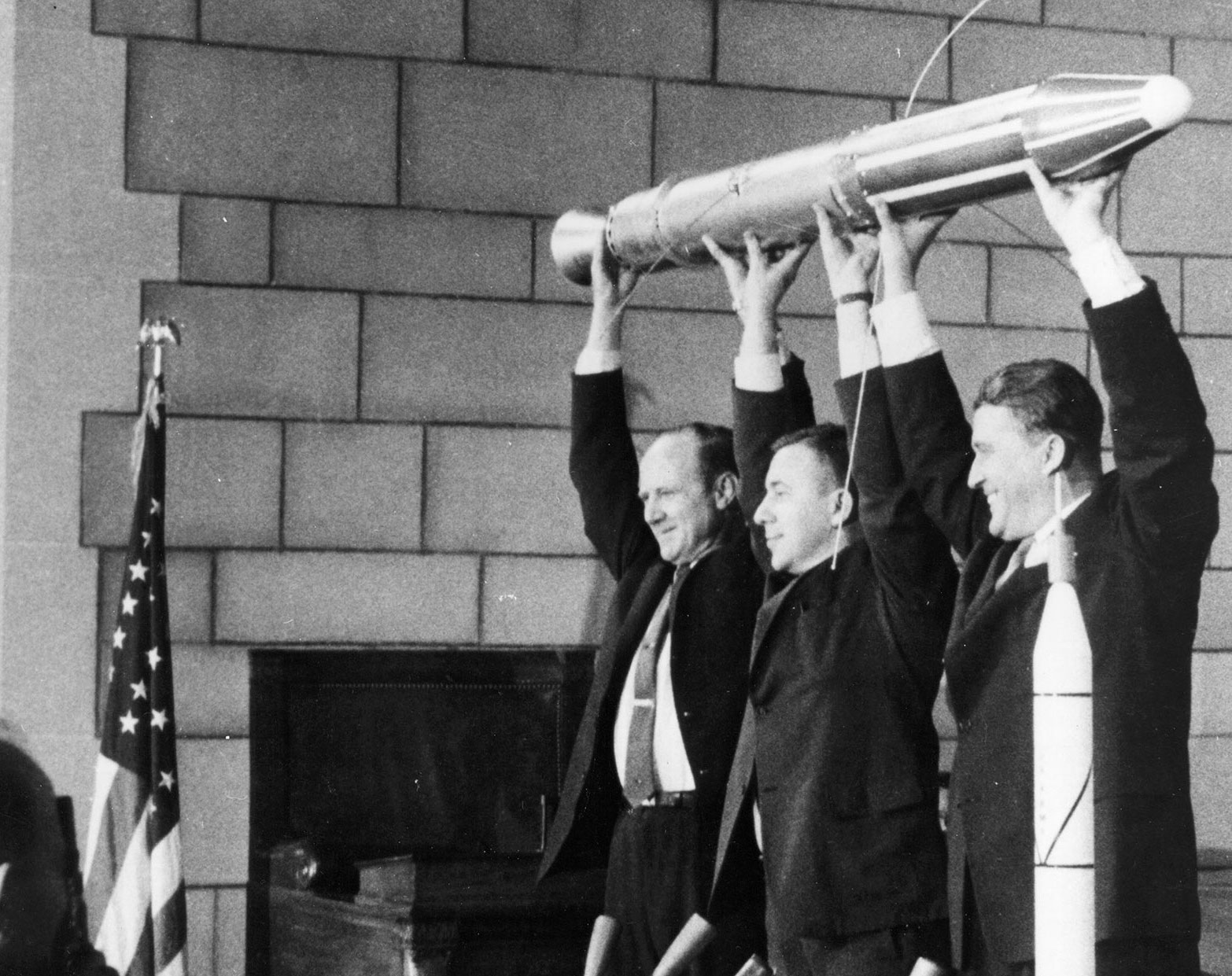 A model of Explorer 1 is held high by JPL Director William Pickering, left; James Van Allen, center; and Wernher von Braun.