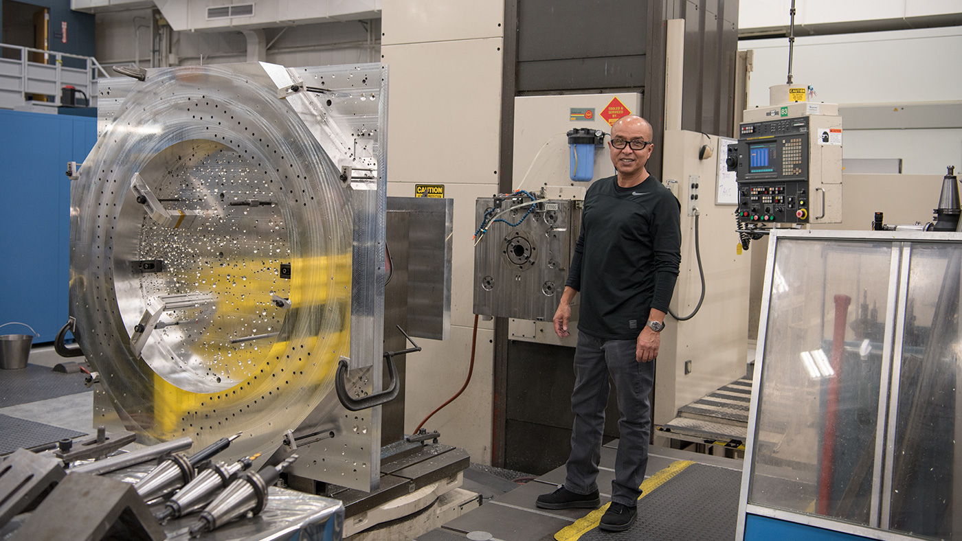 Oscar Avalos stands beside to the Mitsubishi MAF in the machine shop