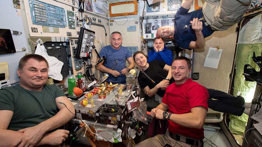 The six-member Expedition 60 crew is gathered together for dinner