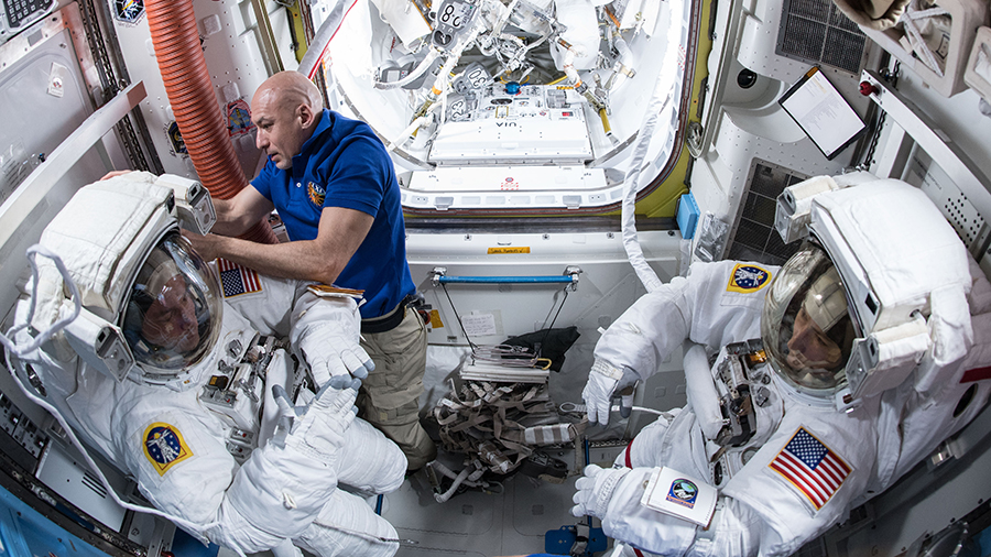 Expedition 61 Commander Luca Parmitano assists astronauts Andrew Morgan and Christina Koch in their U.S. spacesuits