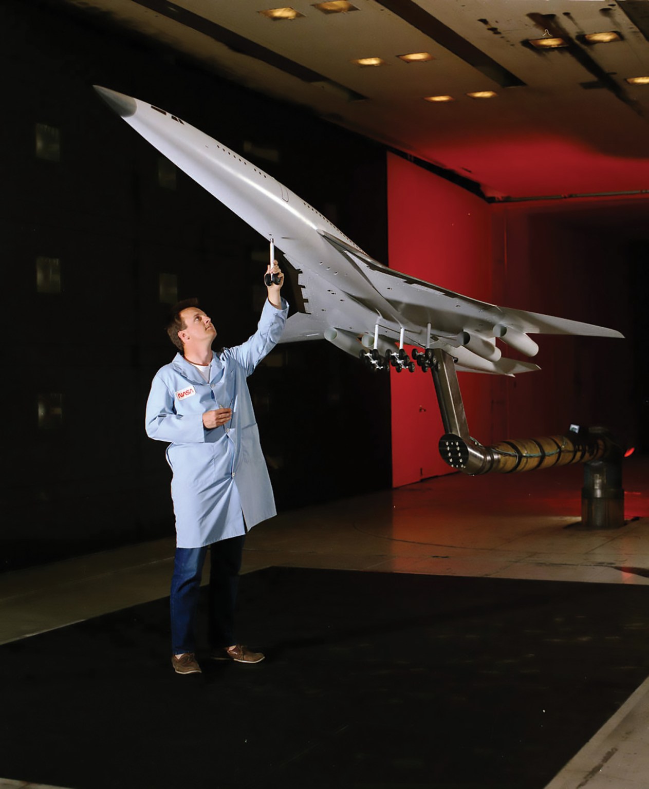 Model of a high-speed aircraft being prepared by a technician for wind-tunnel tests