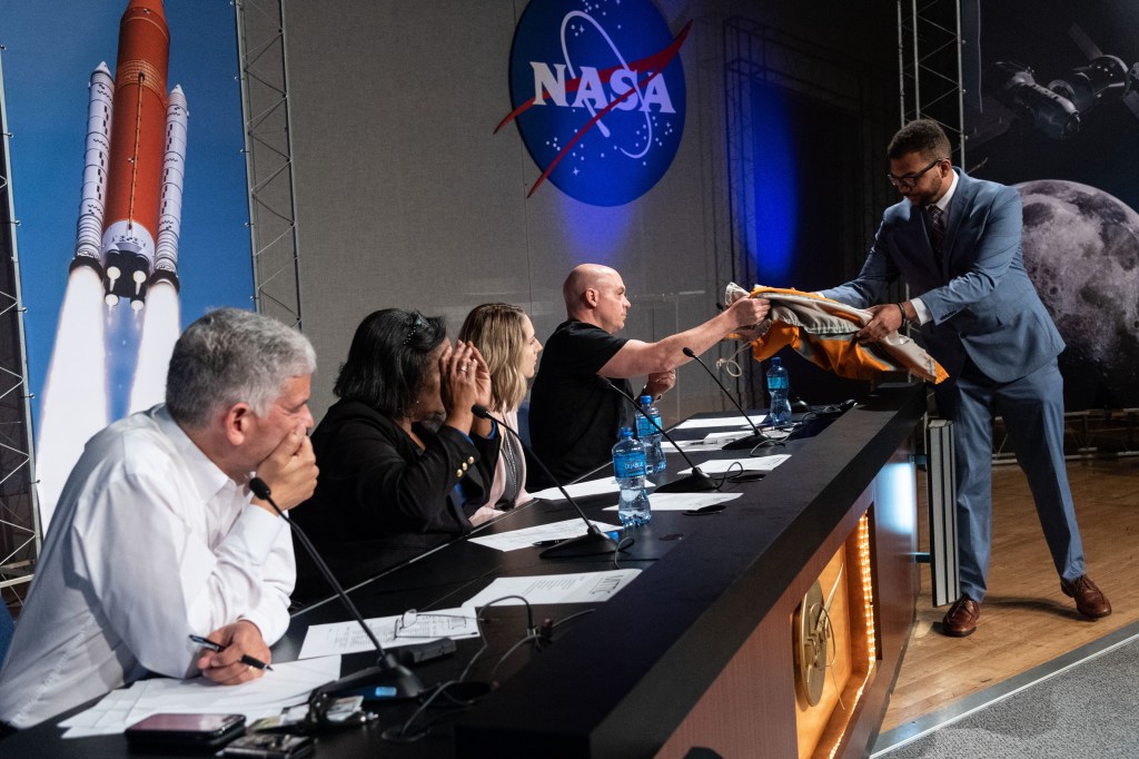 A Student shows an item to a panel of judges.