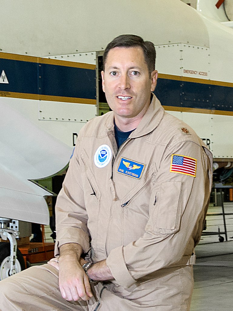 Man in flight suit posed in front of aircraft.