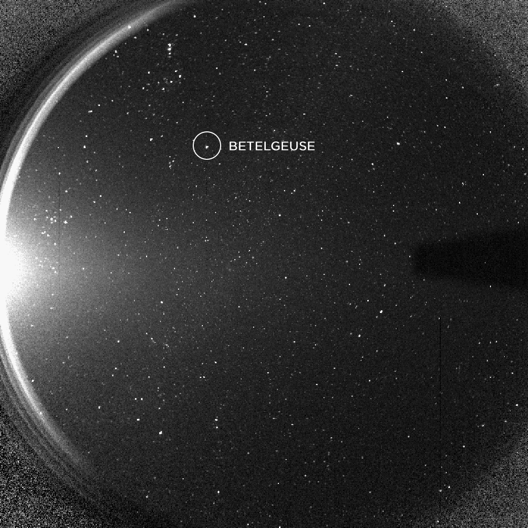 Black-and-white image of stars seen from a spacecraft shows the star Betelgeuse circled and labeled