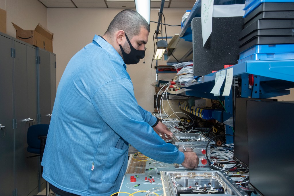 NASA research engineer Jonathan Lopez works on preparing a Compact Fiber Optic Sensing System unit.