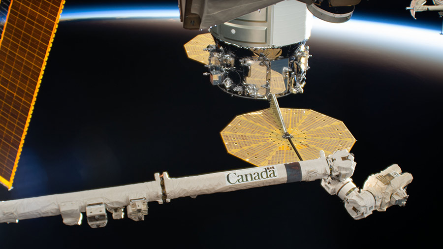 The Canadarm2 robotic arm is extended near the Northrop Grumman Cygnus resupply ship with its prominent cymbal-shaped UltraFlex solar arrays.