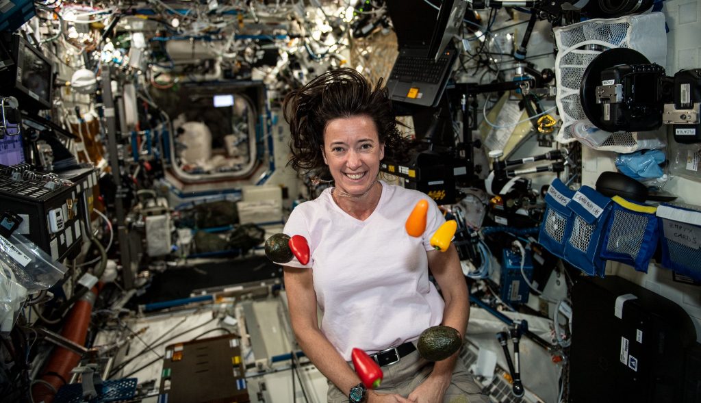 Fresh vegetables float around NASA astronaut and Expedition 65 Flight Engineer Megan McArthur.