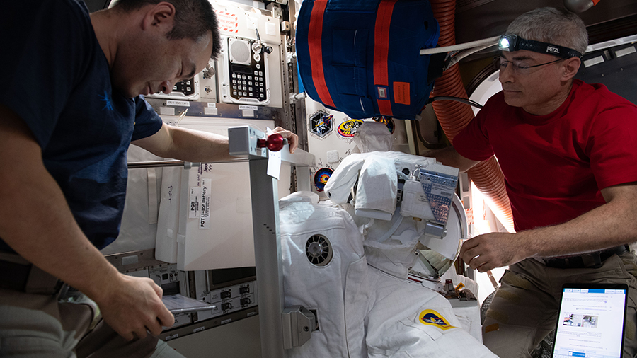 (From left) Astronauts Akihiko Hoshide and Mark Vande Hei install components on a U.S. spacesuit inside the U.S. Quest airlock.