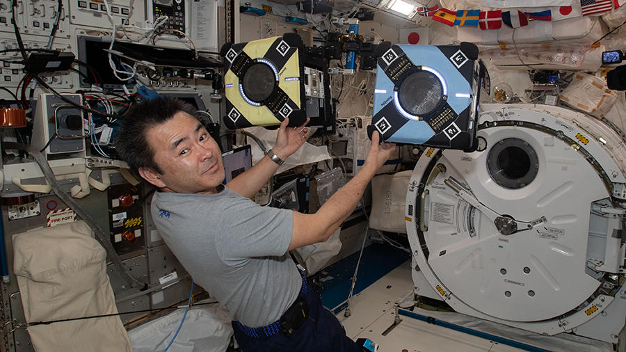 Astronaut Akihiko Hoshide checks out a pair of Astrobee robotic free-flyers inside the Kibo laboratory module.