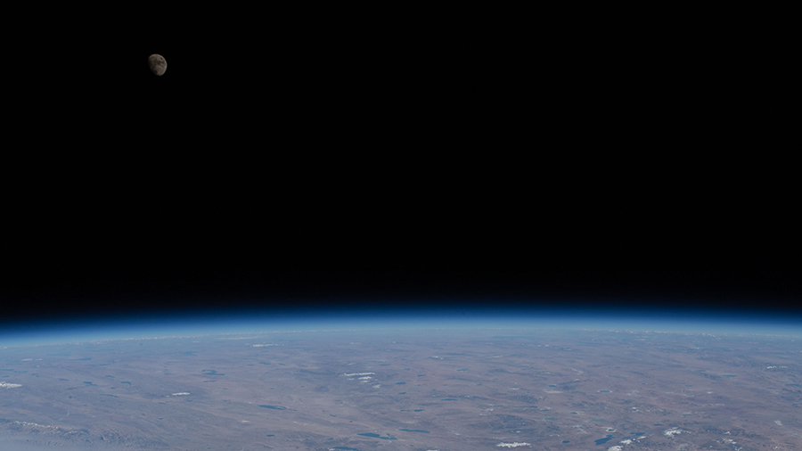 The waxing gibbous Moon is pictured from the space station over Earth's horizon.