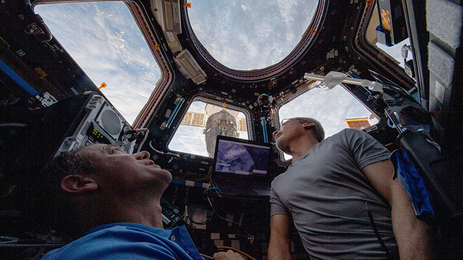 Astronauts (from left) Thomas Marshburn and Mark Vande Hei peer at the Earth below from inside the seven-windowed cupola, the space station's window to the world.