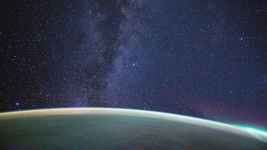 This long-duration photograph from the space station shows the Milky Way above the Earth's horizon with an aurora near the bottom right.