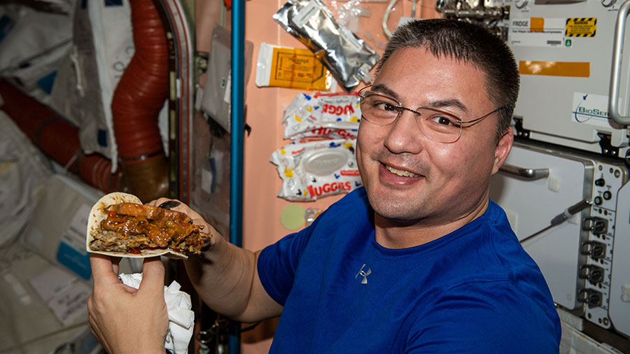 NASA astronaut Kjell Lindgren prepares to enjoy a taco during dinner time aboard the space station.