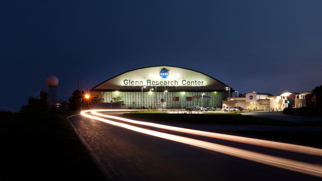 Glenn Research Center Aircraft Hangar at night, with a spotlight on the NASA Meatball logo.