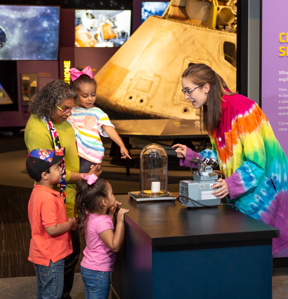 A family interacts with a museum specialist at the Great Lakes Science Center.