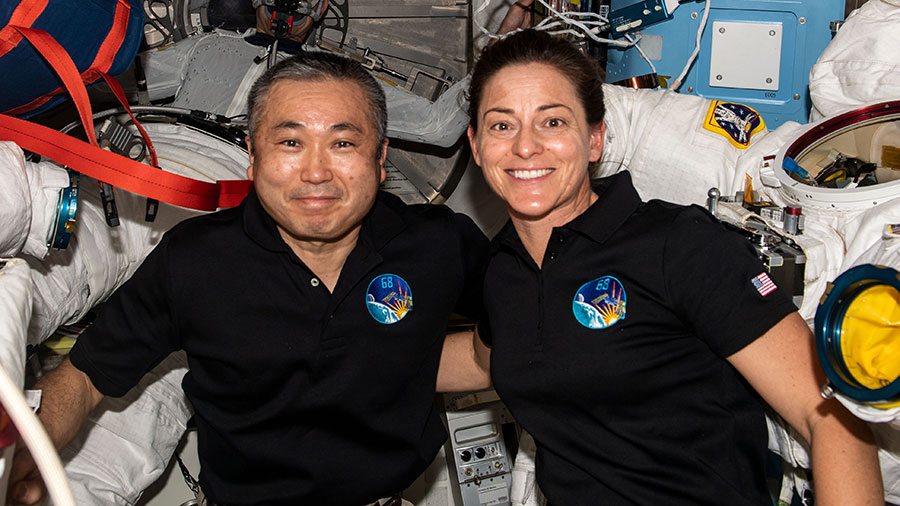 Astronauts Koichi Wakata and Nicole Mann pose with a pair of Extravehicular Mobility Units (EMUs), or spacesuits, aboard the space station.