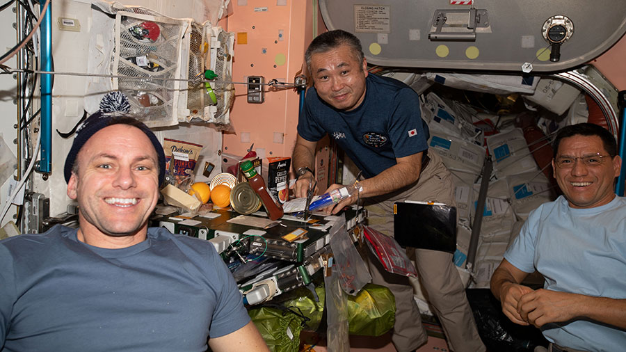 Astronauts (from left) Josh Cassada, Koichi Wakata, and Frank Rubio share a meal on Christmas Eve inside the space station's Unity module.