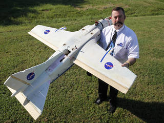 A man holds a model of a small unmanned airplane