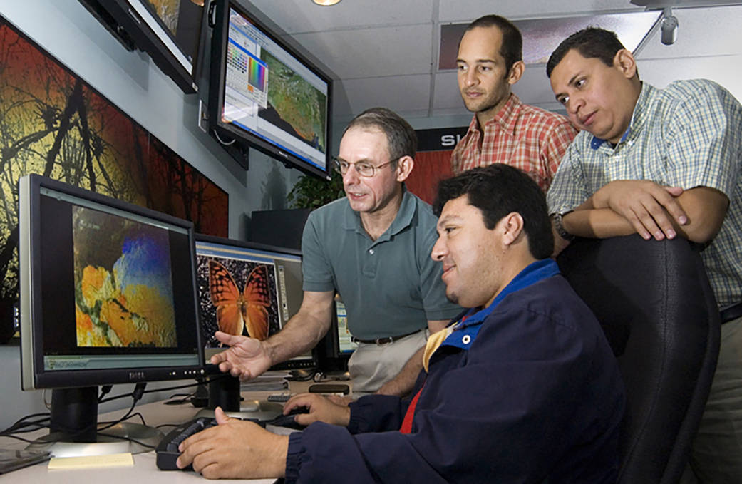 Four men looking at a computer screen