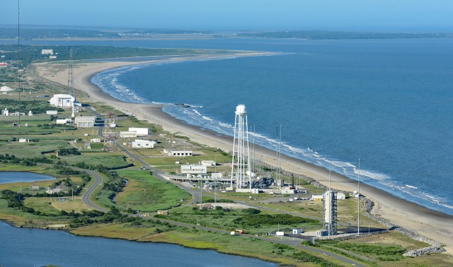 瓦洛普斯飞行设施沿海发射场鸟瞰图，右侧为蓝色大西洋；沿着棕褐色海岸线的白色建筑，映衬出绿色沼泽景观
