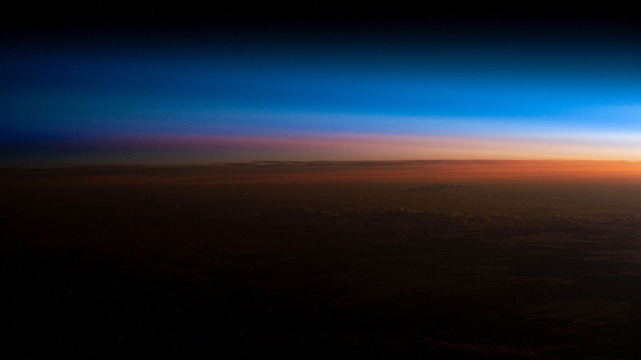 An orbital sunrise illuminates Earth's atmosphere and reveals the cloud tops in this photograph from the space station above southern Brazil.