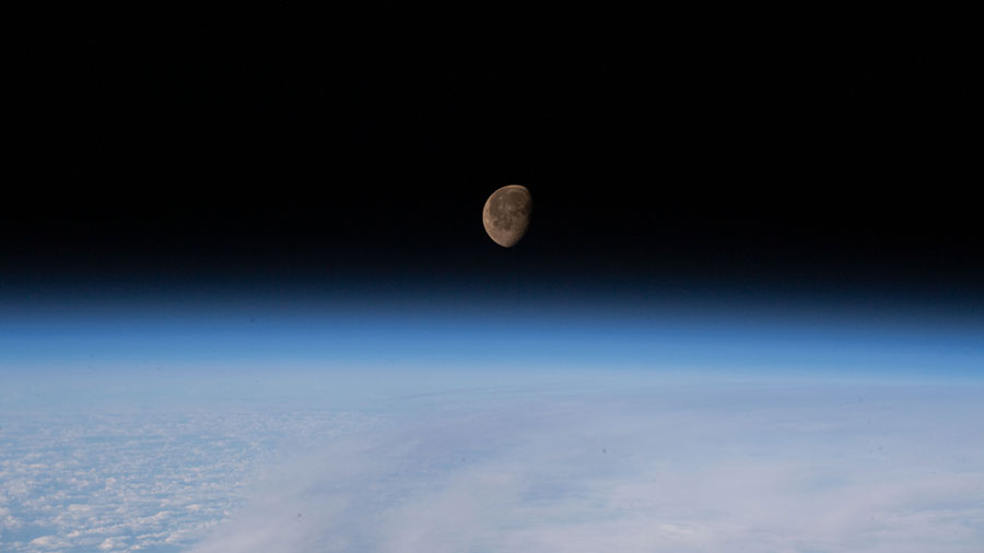 The waning gibbous Moon is pictured above Earth's horizon as the space station orbited above the Pacific Ocean.