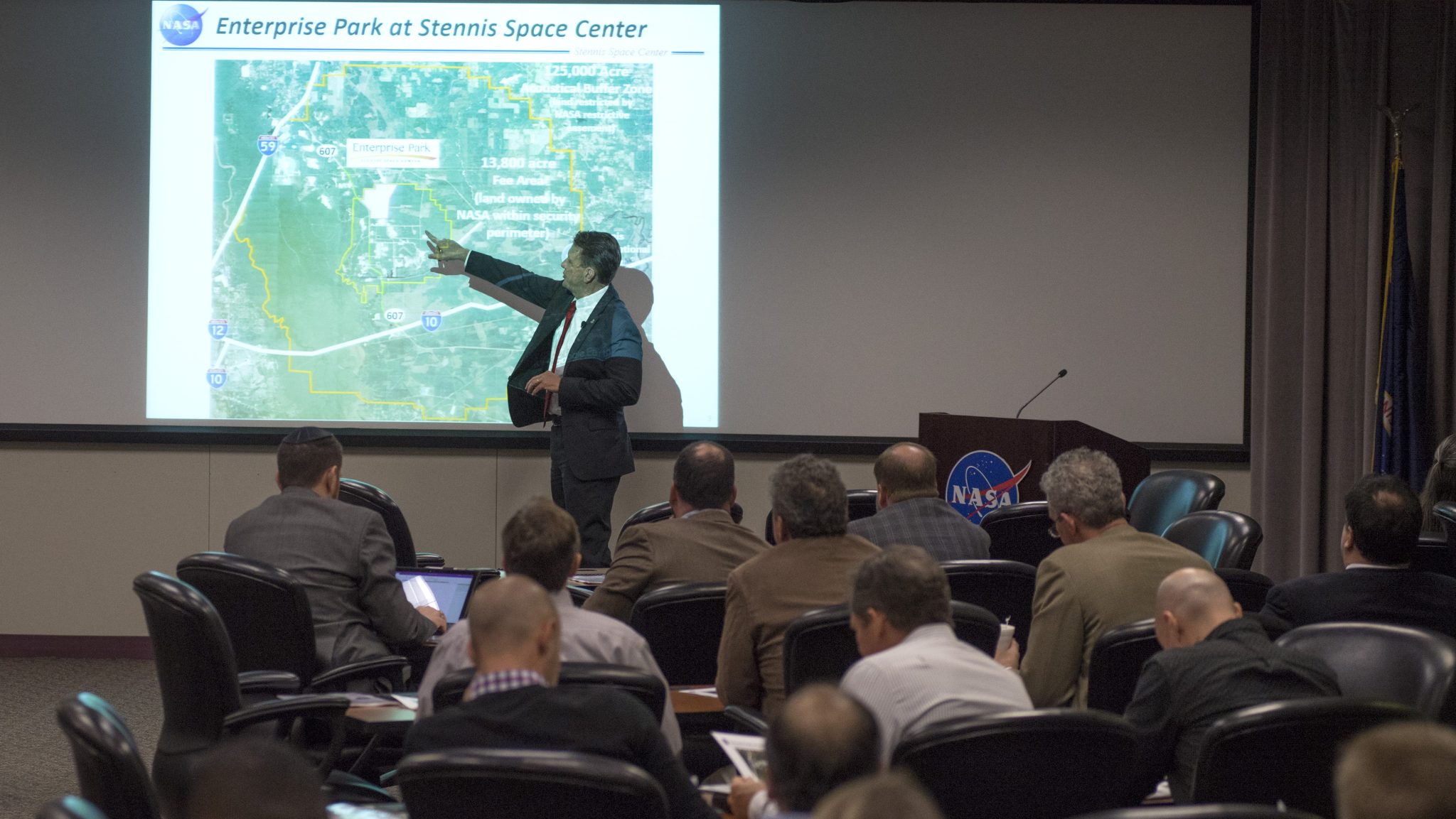 A speaker is presenting a map of the Stennis Buffer Zone to a small audience