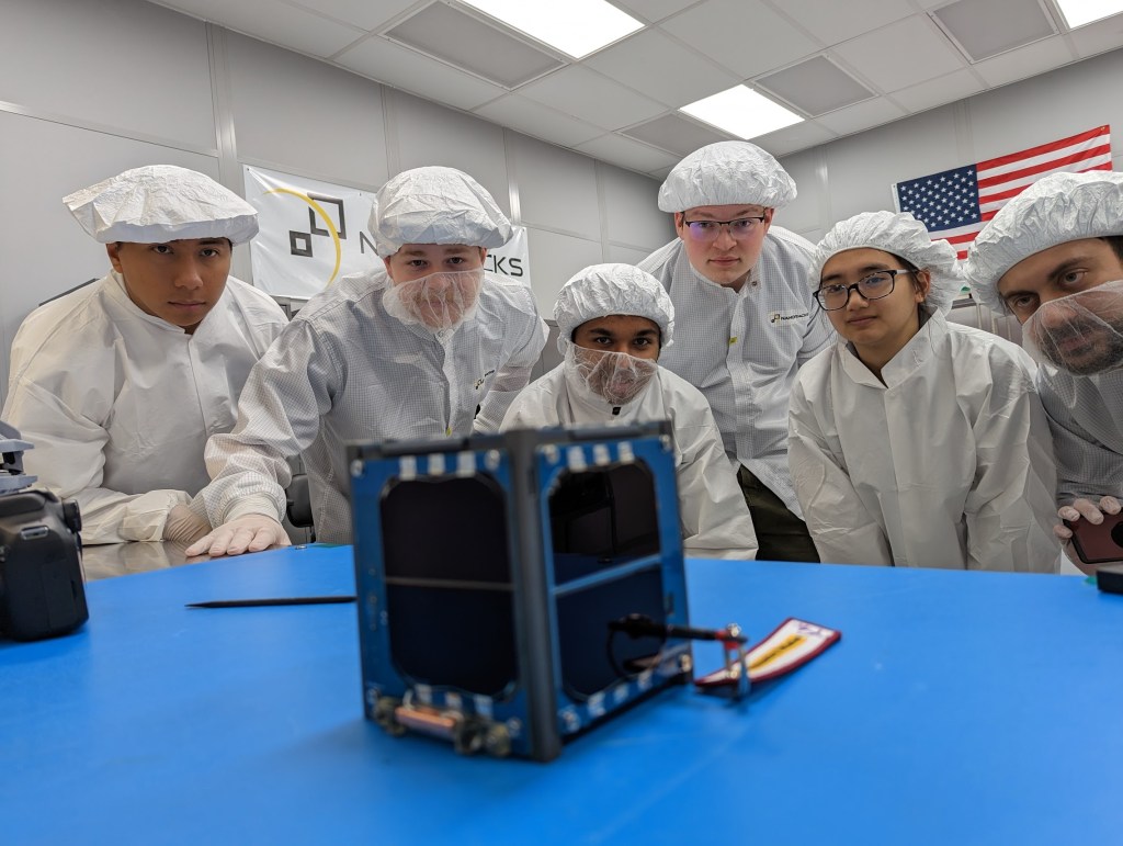 A group of engineering students work on a CubeSat in the laboratory.