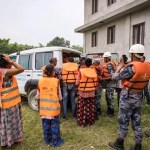 A group of people stand around a van in orange vests working on a flood simulation in Nepal.