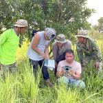 A group of people crouch and stand in a field in Cambodia