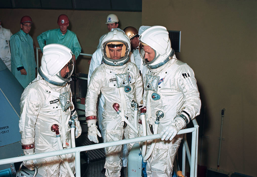 Three astronauts in pressurized spacesuits