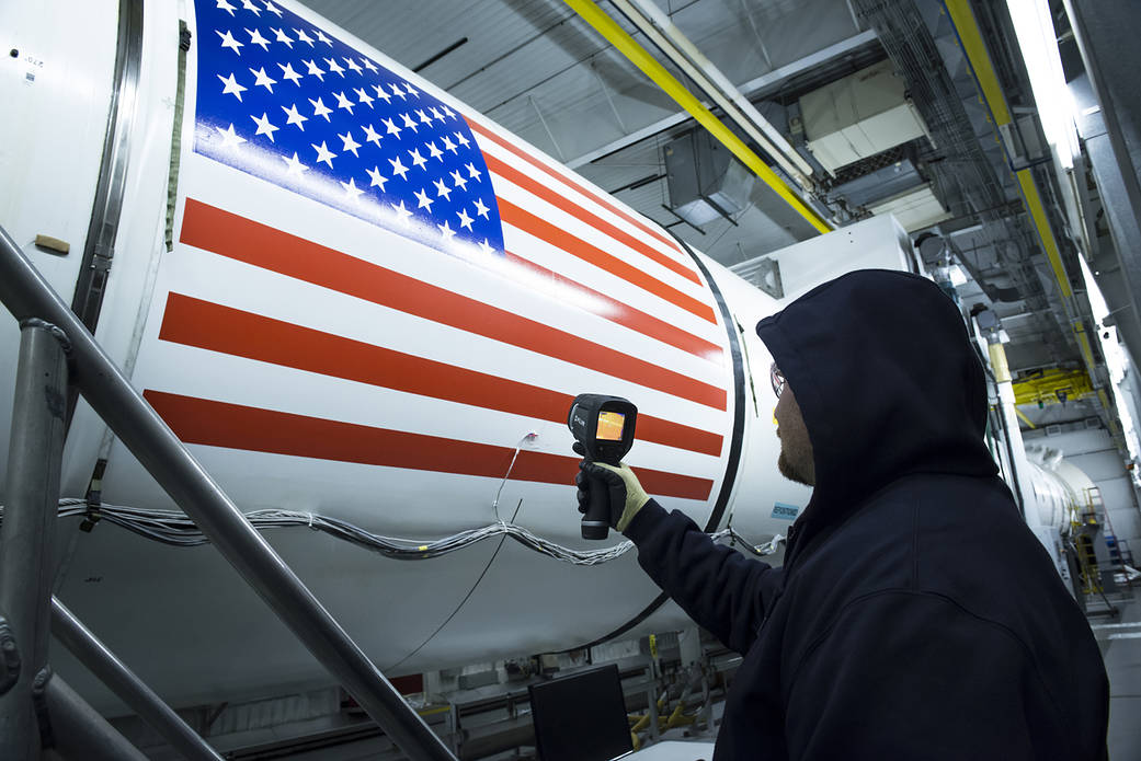 An Orbital ATK technician checks the temperature of a full-scale, test version booster for NASA's new rocket