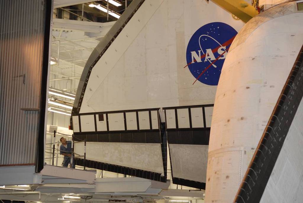 Inside the giant Vehicle Assembly Building at NASA’s Kennedy Space Center in Florida, a technician closely monitors the movement of space shuttle Endeavour as it is lowered into high bay 1 where its external fuel tank and solid rocket boosters wait below.