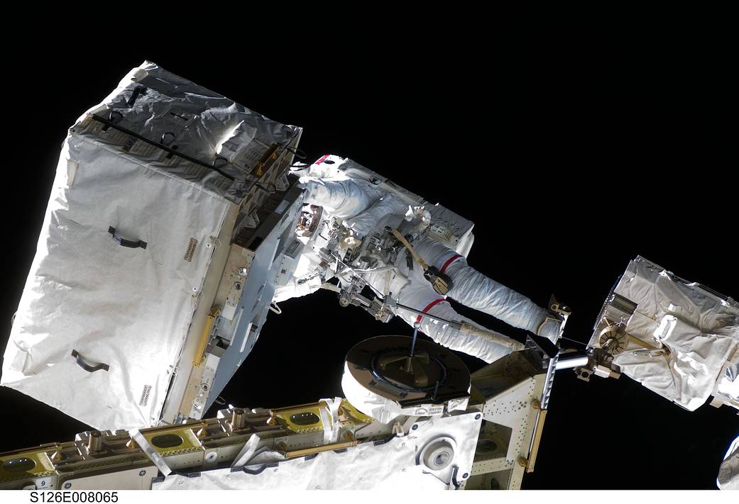 Spacewalking astronaut moving large rectangular object outside space station