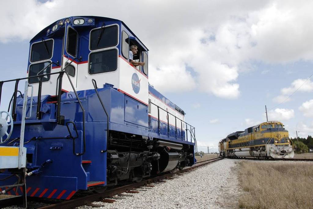 The Florida East Coast Railway train arrives at the Jay Jay Rail Yard with the booster segments for the Ares I-X test rocket for interchange with the NASA Railroad (left).