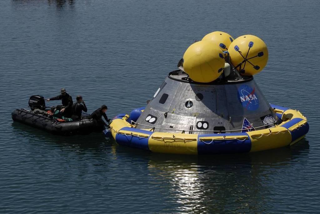 Members of the 920th Rescue Wing secure a flotation collar around the mockup Orion crew exploration vehicle at the Trident Basin at Port Canaveral.