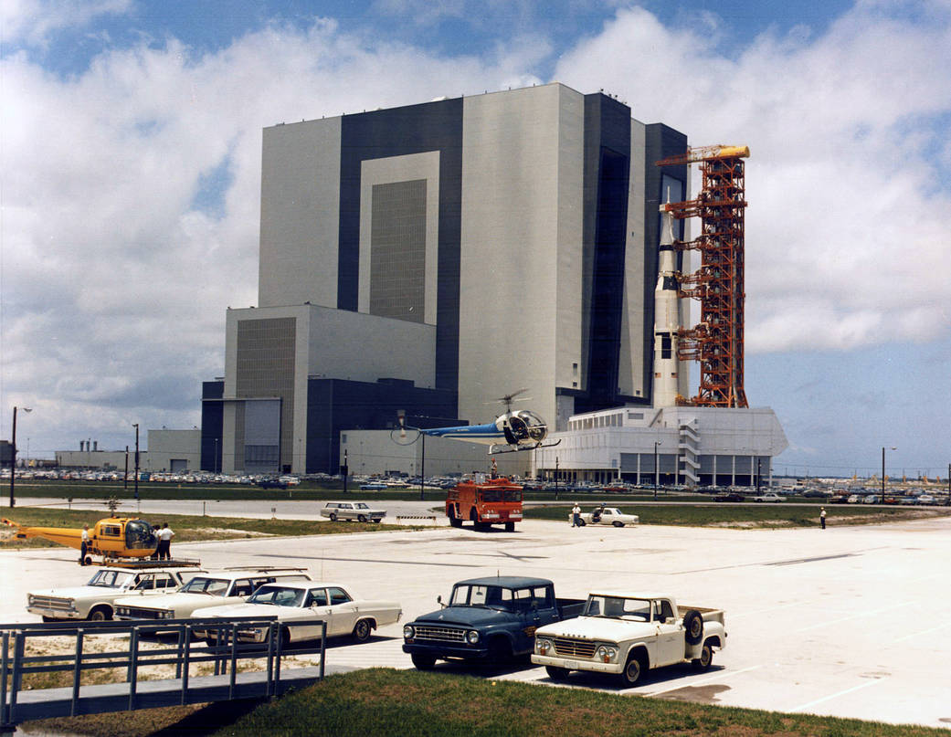 Carrying the Apollo 11 Saturn V rocket and mobile launcher, the crawler inches out of the Vehicle Assembly Building on the journey to Launch Pad 39A. 