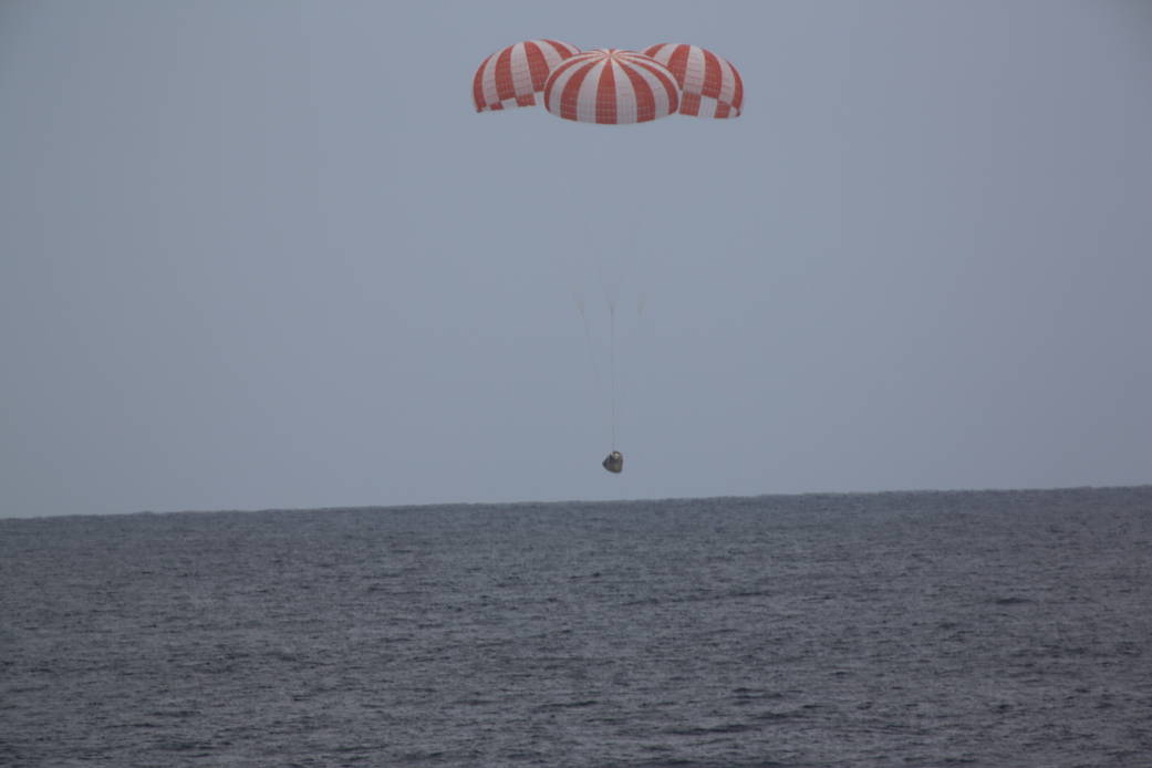 SpaceX Dragon capsule with three parachutes descends to splashdown 