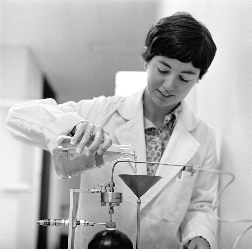 Biologist Caye Johnson pouring a liquid into a funnel.