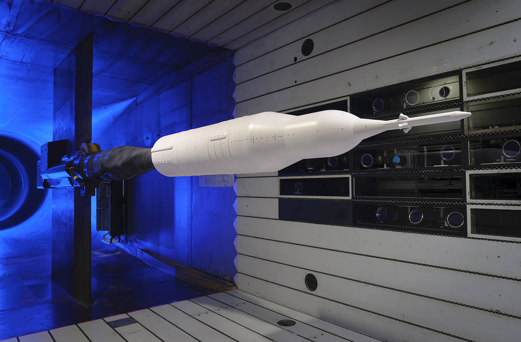 model of Space Launch System rocket in wind tunnel blue light behind it