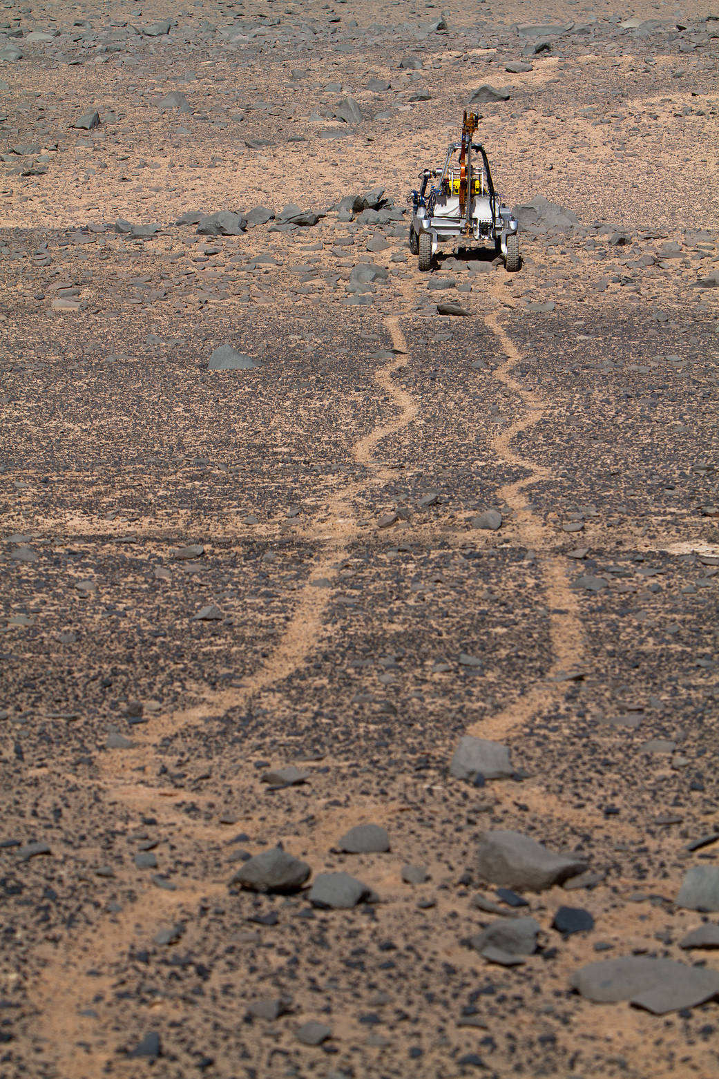 The ARADS rover venturing off in the Atacama Desert, leaving tracks in the sand behind it.