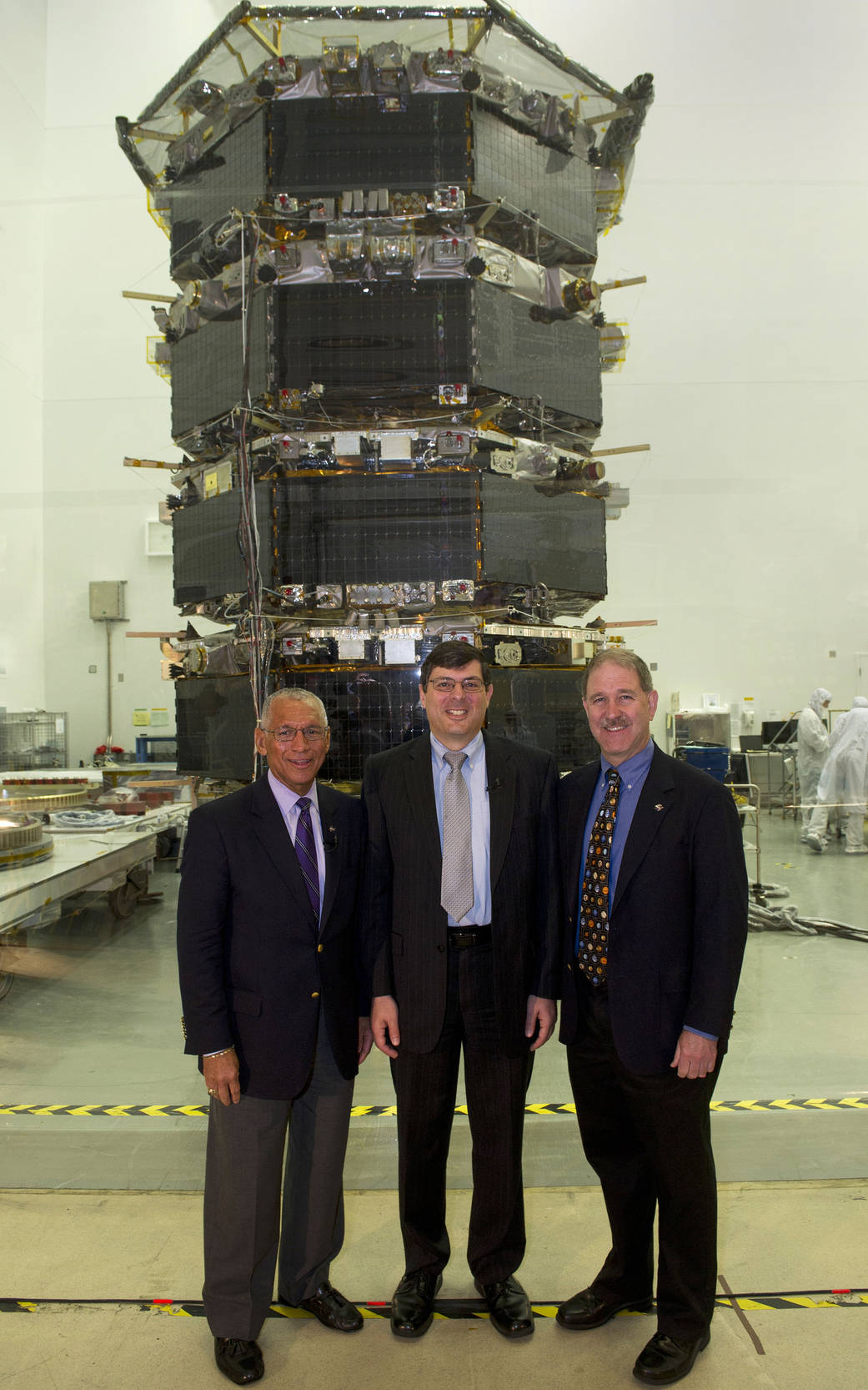 Posing in front of the stacked MMS spacecraft are (left to right): Charles Bolden, Chris Scolese and John Grunsfeld.